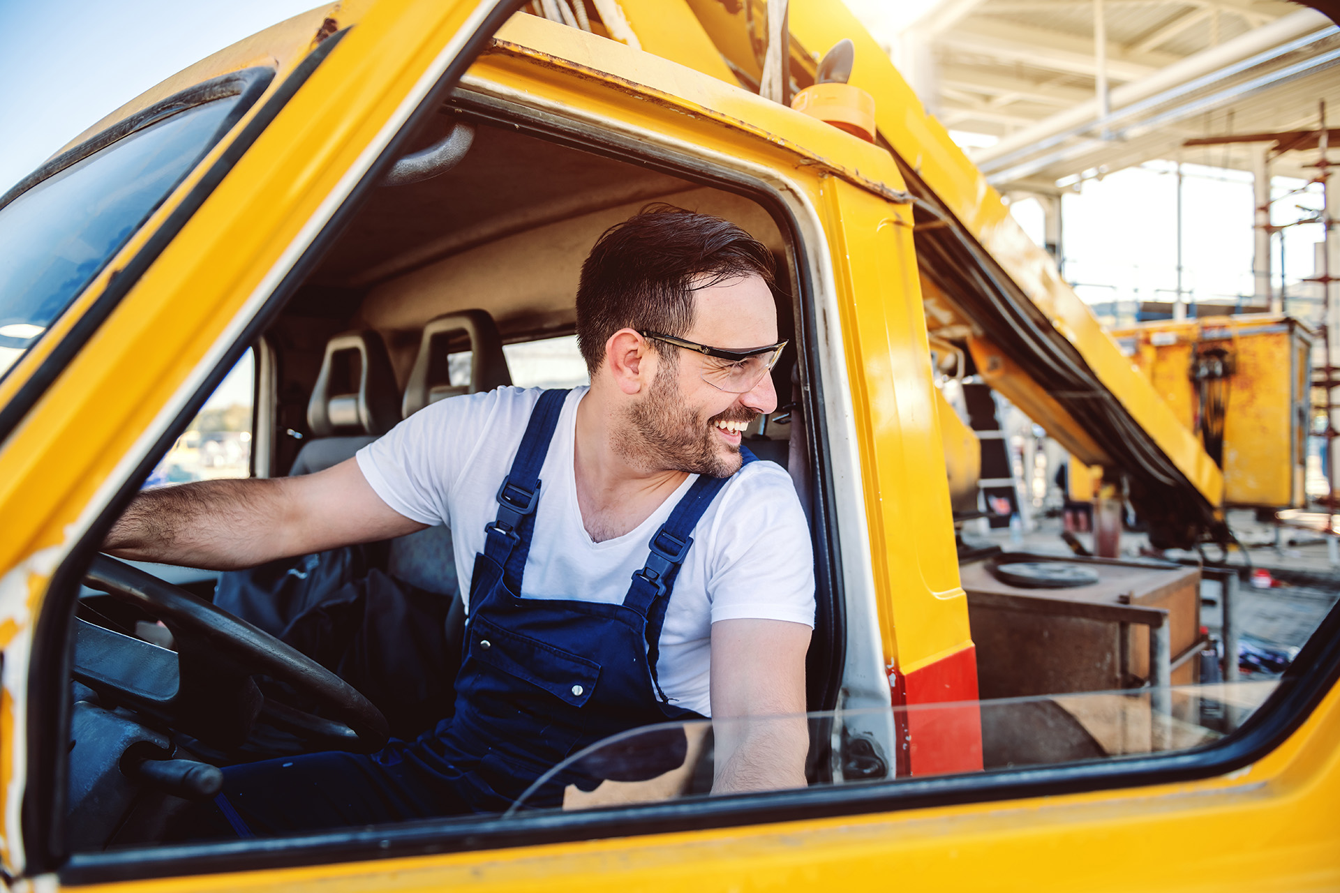 Smiling handsome caucasian worker in overall entering excavator